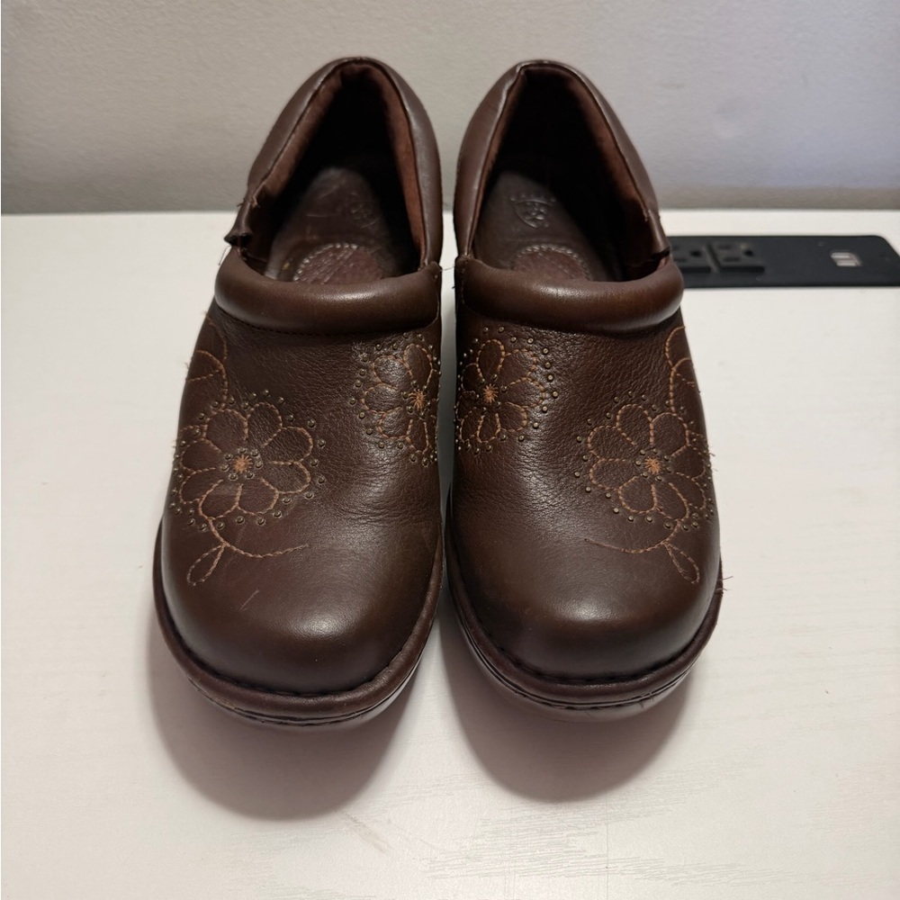 Women’s Ariat leather clogs in brown with a floral design and studded accents.